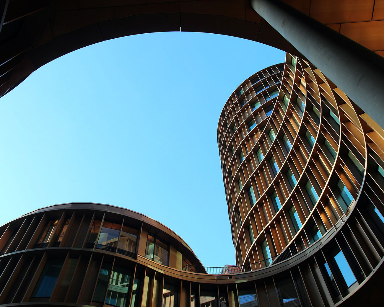 Een hoog flatgebouw, met golvende lijnen en houten buitenafwerking, bekeken uit kikvorsperspectief.